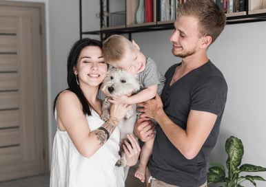 a man and woman holding a baby and a dog