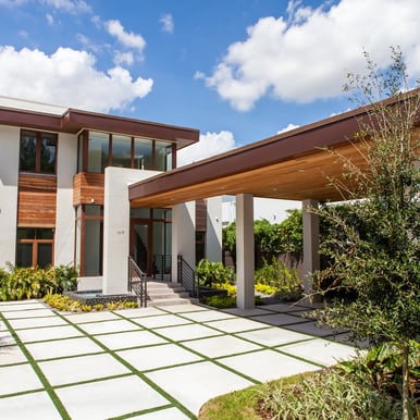 carport and entrance way to a white custom luxury home with plank accents