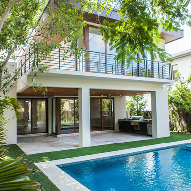 a backyard to a white luxury custom home with a pool and grill and plants