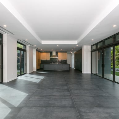 an open and spacious unfurnished living room leading to an open kitchen with black floors 