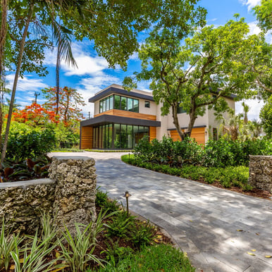 brick driveway leading to a vibrant front yard of a custom built luxury home