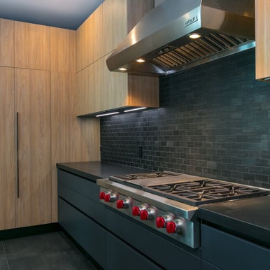 a black countertop and stovetop with a large wooden storage space