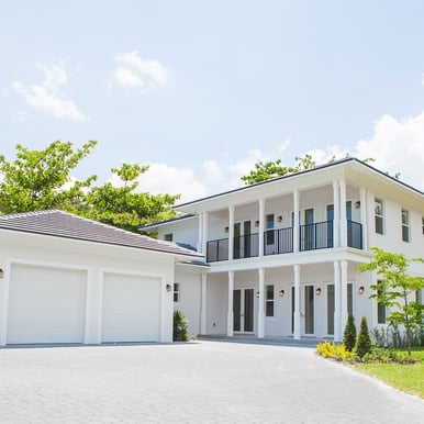 a white luxury home with a large driveway shown and a two door garage