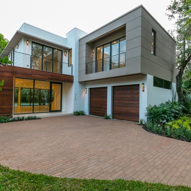 a brick driveway to a square looking custom designed luxury home