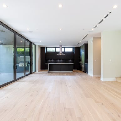 unfurnished interior of a luxury home's living room and kitchen island with parquet floors