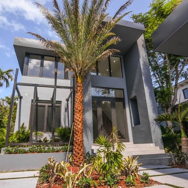 Modern Modular shaped house with palm trees and a gate and walkway