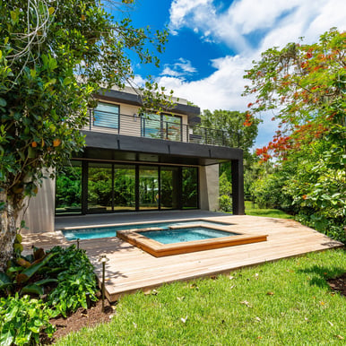 a medium sized luxury home backyard showing vibrant foliage, swimming pool with hot tub and deck