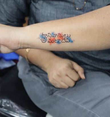 Name tattoo with orange and blue watercolor effect on hand by Dudo’s Hyderabad