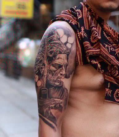 Realistic Shiva face tattoo on shoulder by Dudo’s Tattoos and Piercing in Hyderabad