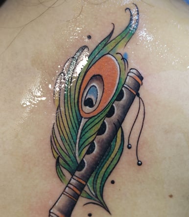 Flute with peacock feather watercolor fill by Dudo's Tattoos Hyderabad