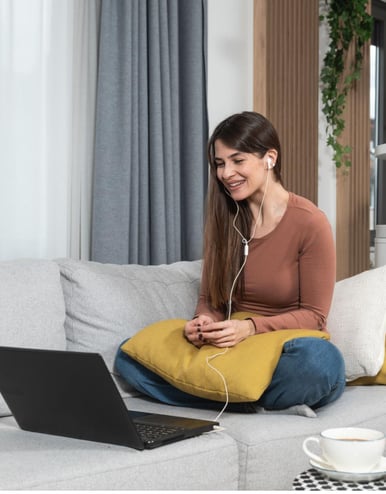 a woman sitting on a couch with a laptop and headphones