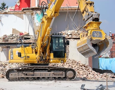 Pelle mécanique sur un chantier de démolition, avec des gravats, une structure partiellement démolie