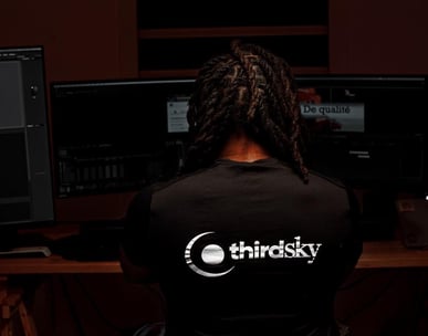 a man sitting at a desk with a computer monitor and a keyboard making film editing 