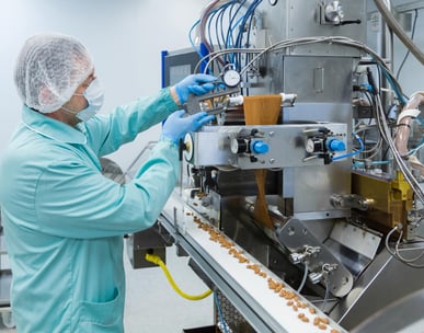 a person in a lab coat and gloves working on a machine