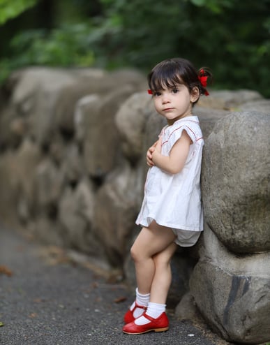 a little girl standing on a rock wall