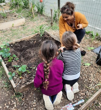 animatrice sensibilisant des enfants à l'environnement par la création d'un potager pédagogique