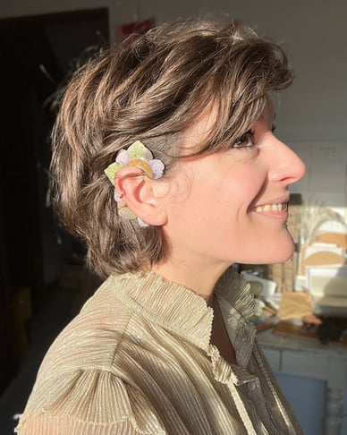 portrait de la créatrice Charlie O'Plumes portant un earcuff en pétales d'hortensia dans son atelier