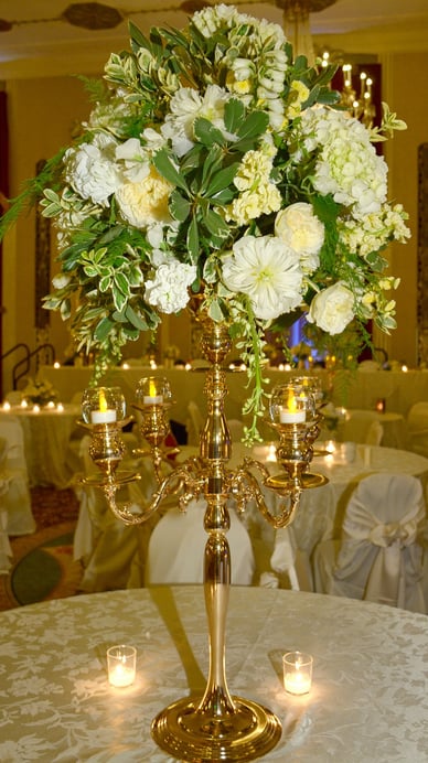 a tall gold fancy candle holder with candles and flower