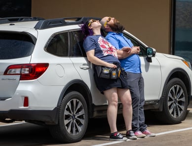 A couple lays against the side of their car to watch the progression of the solar eclipse together. Photo by Taylor Pleasant
