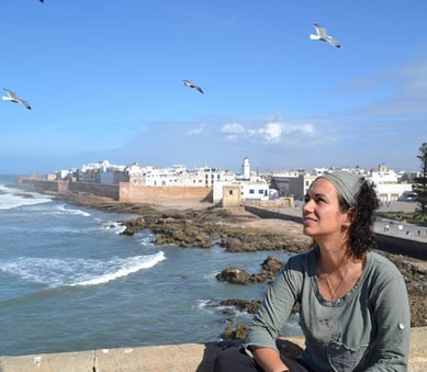 a woman sitting on a ledge looking out over the ocean beatriz alvarez
