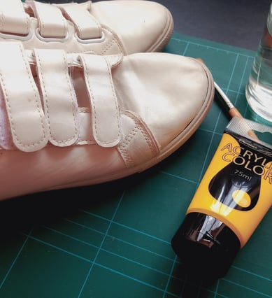 a pair of shoes and a acrylic paint on a table