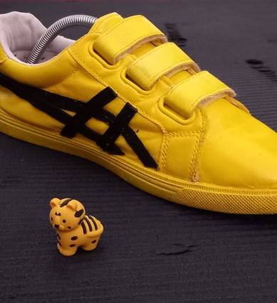 a yellow and black shoe with a toy tiger