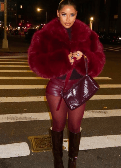 a woman in a red coat and boots is walking across the street