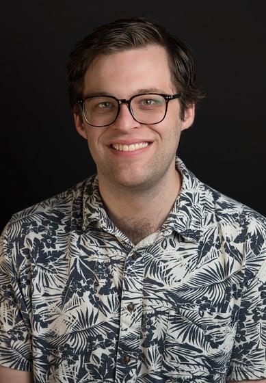 a man in a blue shirt and glasses with big smile