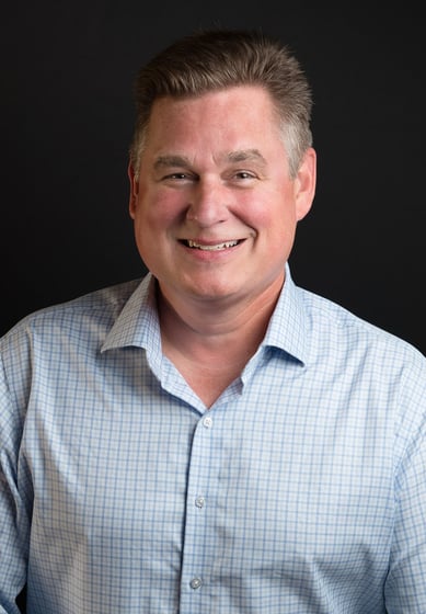 a man in a blue shirt and a white shirt smiling