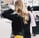A woman with long blonde hair wearing a black coat walking outside