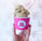 a person holding a cupcake in a pink cup