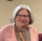 Woman with gray hair and glasses smiling.