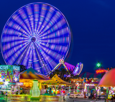 a ferris wheel at night time with people walking around