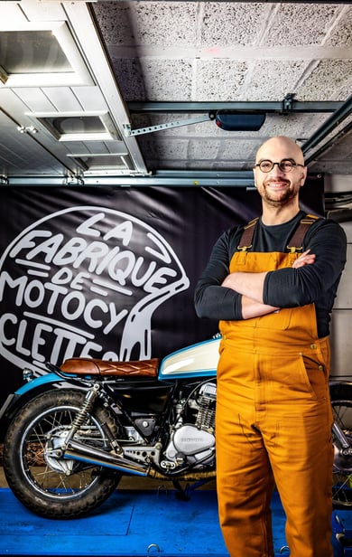 un homme en bleu de travail et en bleu de travail devant une moto