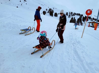 a woman is pulling a sled with a child in a sled