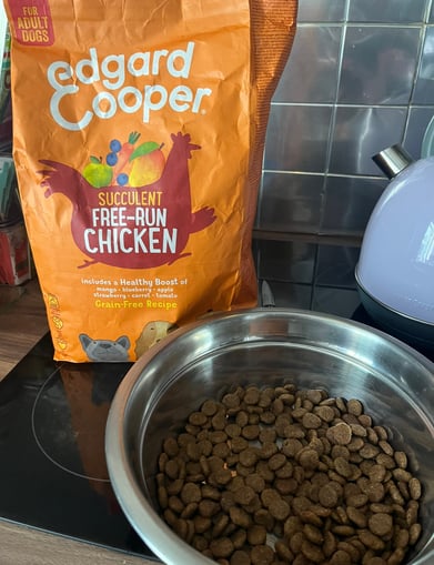 Close-up of Edgard & Cooper kibble in a dog bowl with packaging in the background