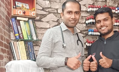 Two men Dr Ansul Sachan and Navneet standing in front of a desk with a laptop