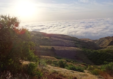 a mountain view of a valley with clouds