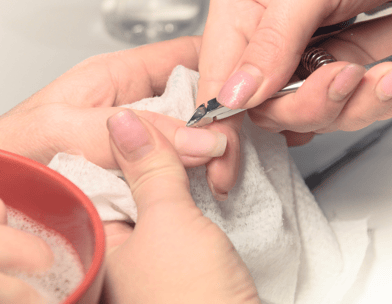 Someone is performing a manicure and using a cuticle trimmer for precision