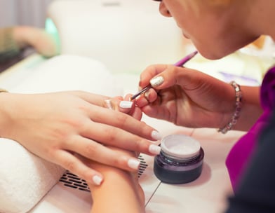 A lady receiving a nail treatment from a meticulous manicurist