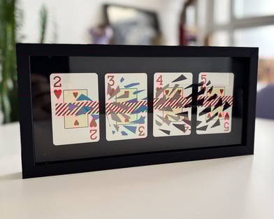 imagem da obra, composta por 4 cartas de baralho com intervenções de washi tape e fita isolante, emolduradas com fundo preto.