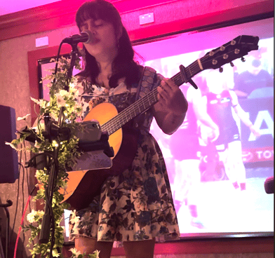 a woman in a dress and a guitar in front of a microphone