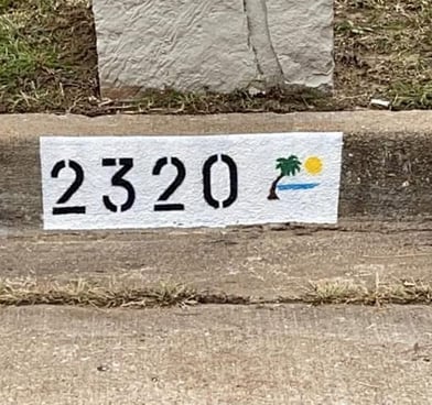 Address "2320" painted with a palm tree at the beach.