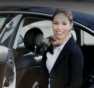 a woman in a suit and tie is standing in front of a chauffeur car