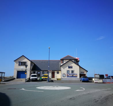 Borth RNLI Lifeboat station veiwed from the mini roundabout with blue skies