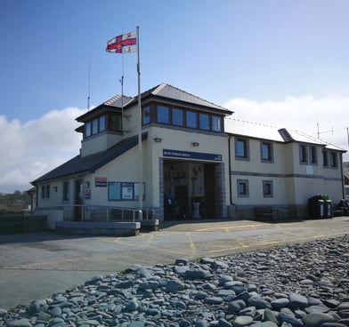 Borth RNLI Lifboat station viewed from the slipway and beach with blue skies