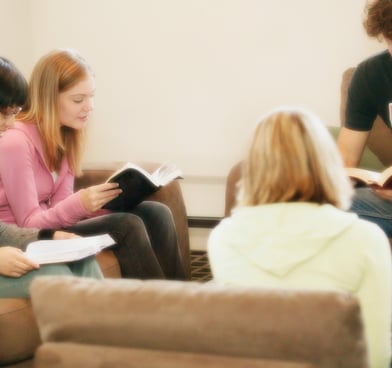 Group of diverse people in living room holding Bibles, sharing enlightenment concepts