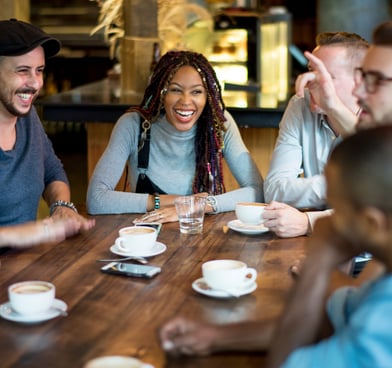 Diverse group gathered around a table joyfully discussing metaphysical concepts