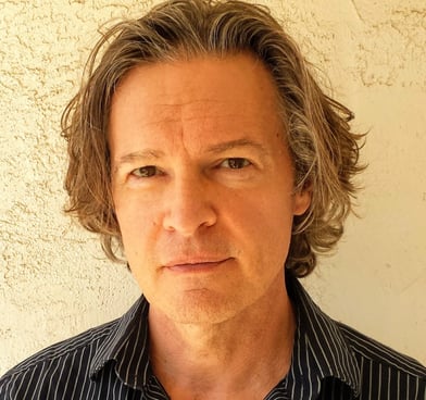 Todd Long with medium-length hair and serious expression