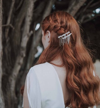 Bride in white wedding dress and loose curls, wearing pearl hair pins and a braid